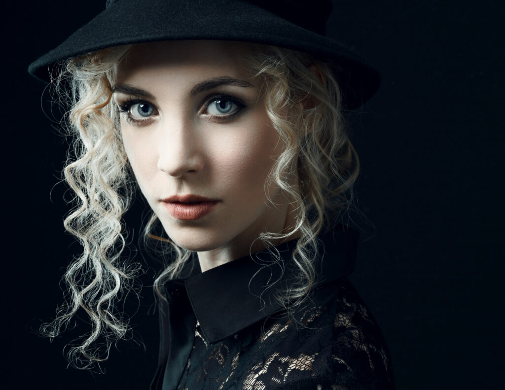 Photograph of beautiful young woman dressed in black with blond curly hair