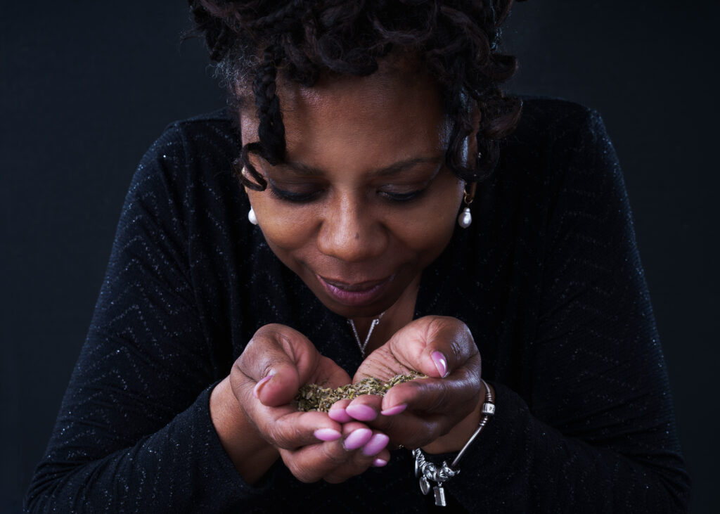 Woman in low-key lighting, holding tea leaves