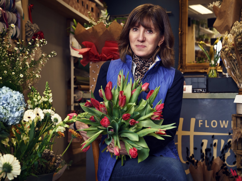 Charlotte holding a bunch of red tulips in her flower shop